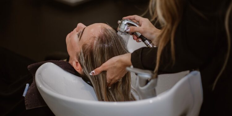 A woman relaxing during a scalp treatment at a Tokyo hair salon, eyes closed as a therapist works gently on her scalp