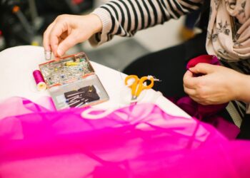 A volunteer helps a woman mend a jacket at a repair café in Tokyo, showing community mending in action.