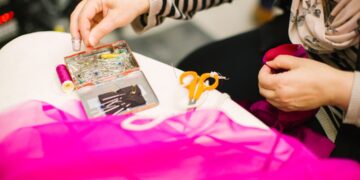 A volunteer helps a woman mend a jacket at a repair café in Tokyo, showing community mending in action.