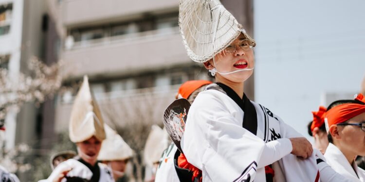 woman-wearing-yukata-street-festival-unsplash - TOKYOwebzine woman in a vintage yukata walks through a Tokyo street market, representing the beauty of yukata fashion during Obon season.