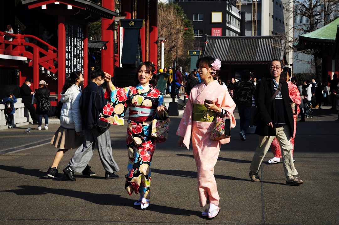 Two friends browse colorful garments at a Tokyo vintage market, discovering secondhand yukata fashion with care and joy.