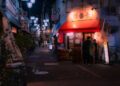 A local shopkeeper assists a customer inside a Tokyo shotengai investment property on a covered neighborhood shopping street.