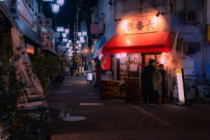 A local shopkeeper assists a customer inside a Tokyo shotengai investment property on a covered neighborhood shopping street.