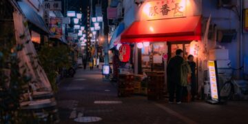 A local shopkeeper assists a customer inside a Tokyo shotengai investment property on a covered neighborhood shopping street.