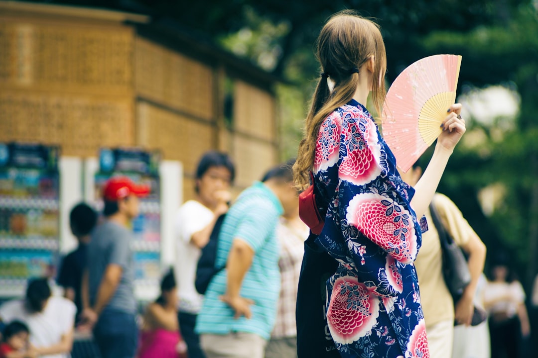 Una mujer en Tokio usa un abanico plegable tradicional para mantenerse fresca en un caluroso día de verano, un ritual sencillo que funciona maravillosamente.
