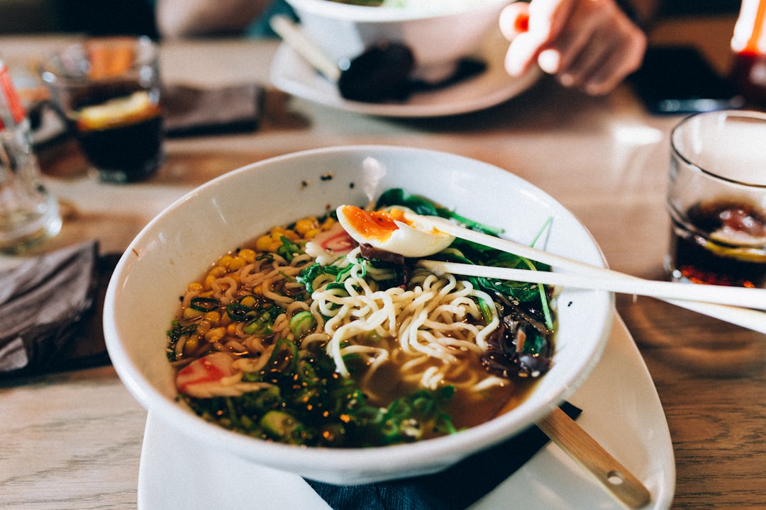 A woman enjoying a bowl of gluten-free ramen at a Tokyo noodle restaurant, smiling over her wheat-free meal.