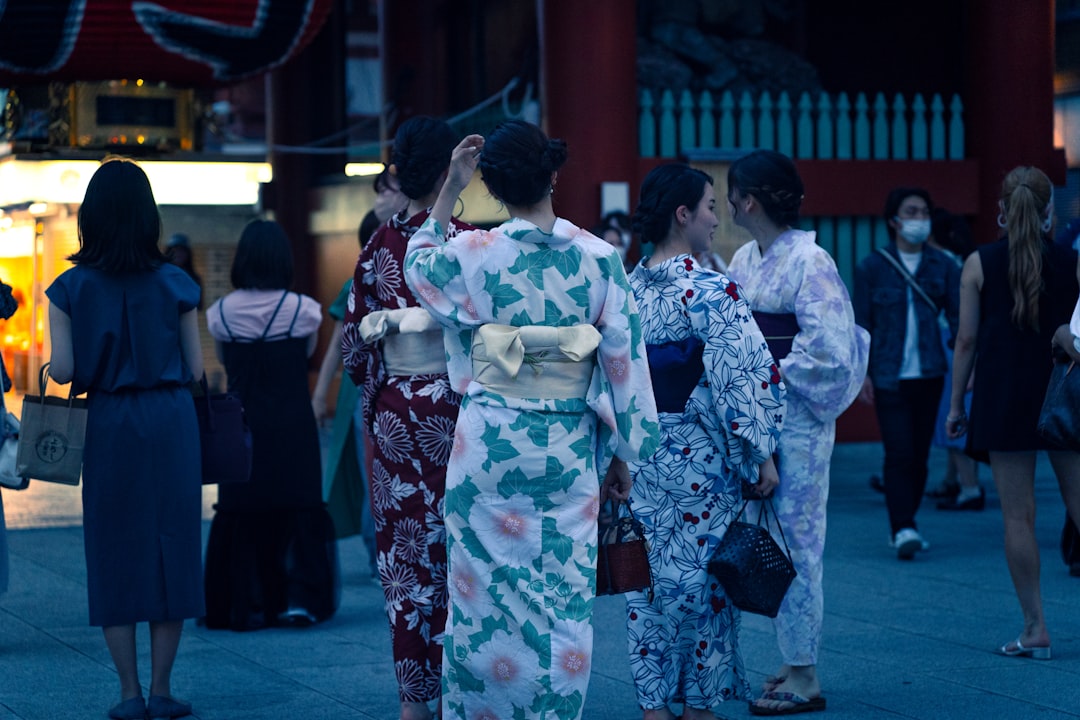 Una mujer con yukata sonríe mientras observa el espectáculo de fuegos artificiales Hanabi Tokyo por la noche, rodeada de una multitud de asistentes al festival.