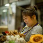 A shopper carefully selecting fresh sashimi trays at a Tokyo depachika basement food hall