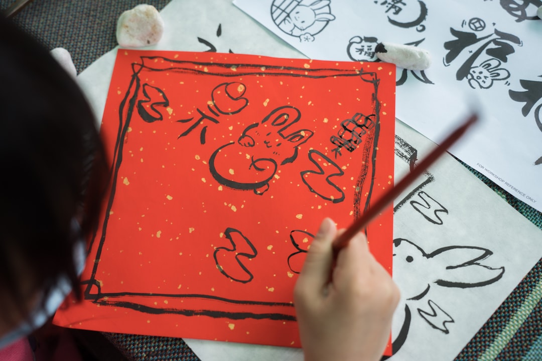 A young child concentrates on a brush painting activity during summer kids workshops in Tokyo, surrounded by mineral pigments