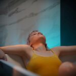 A woman in a float therapy pod at a Tokyo wellness studio, preparing for a session of sensory rest.