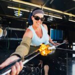 A woman works with molten glass during workshop