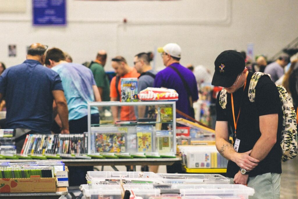 A visitor carefully browsing doujinshi at a Comic Market circle table inside Tokyo Big Sight