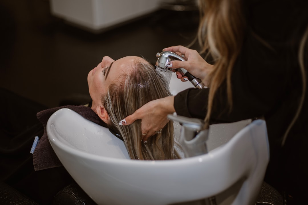 A woman relaxing during a scalp treatment at a Tokyo hair salon, eyes closed as a therapist works gently on her scalp
