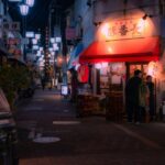 A local shopkeeper assists a customer inside a Tokyo shotengai investment property on a covered neighborhood shopping street.